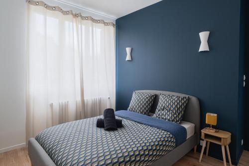 une chambre avec un lit avec un mur bleu dans l'établissement T2 Evasion des 24h - Le Mans, au Mans