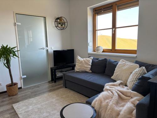 a living room with a blue couch and a tv at Glanz und Gloria Weingartenapartment an der Kellerstraße, viele Buschenschänke, sehr ruhige Lage, herrliche Aussicht! in Leutschach