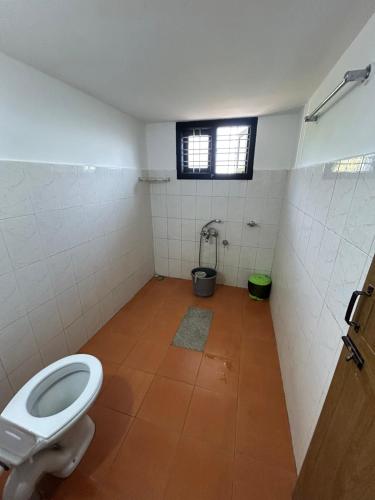 a bathroom with a toilet and a window at Mountain View Villas in Madikeri