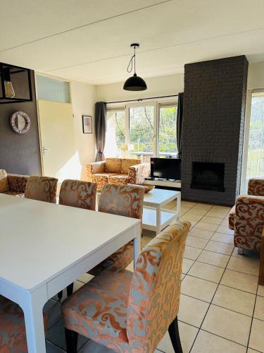 a living room with a table and chairs and a fireplace at Recreatiebungalow Lochem in Lochem