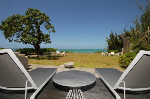 a patio with a table and chairs and the ocean at Beachfront & Pool Poste Lafayette in Poste Lafayette