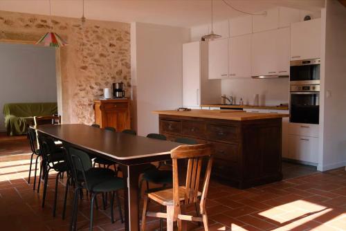 eine Küche mit einem Tisch und Stühlen sowie eine Küche mit weißen Schränken in der Unterkunft Gîte du Moulinet in Chézy-sur-Marne