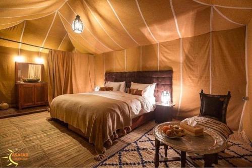 a bedroom with a bed and a table in a tent at Asafar Luxury Camp in Merdani