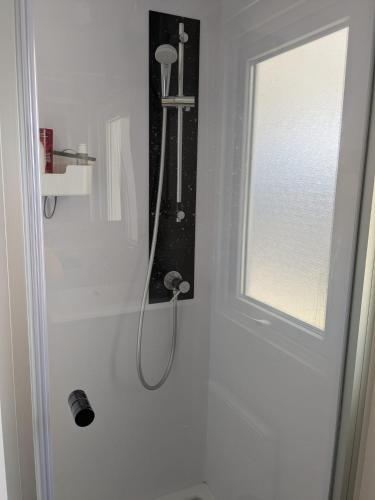 La salle de bains blanche est pourvue d'une douche et d'une fenêtre. dans l'établissement Chez Bruno & Sophie Mobil home luxe 6-8P BORA BORA, à Saint-Julien-en-Born