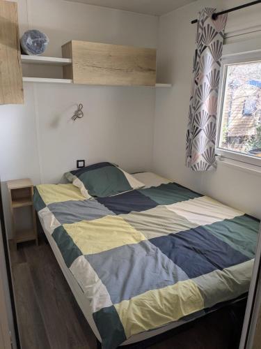 - une chambre dotée d'un lit avec une couverture bleue et jaune dans l'établissement Chez Bruno & Sophie Mobil home luxe 6-8P BORA BORA, à Saint-Julien-en-Born