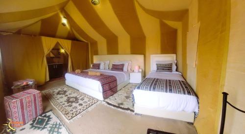 two beds in a room with yellow walls at Asafar Luxury Camp in Merdani