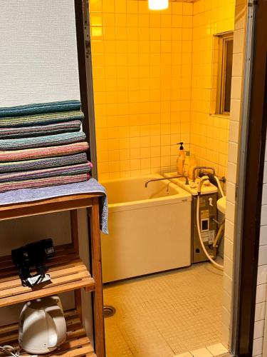 a bathroom with a tub and a sink and yellow tiles at ZYZSumiyoshichō 2K SJ0254 in Tokyo