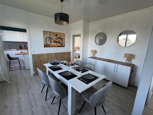 une salle à manger avec une table et des chaises blanches dans l'établissement les dunes proche plage jardin, à Urville-Nacqueville