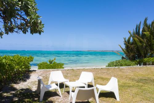 four white chairs sitting on the grass near the ocean at Beachfront & Pool Poste Lafayette in Poste Lafayette