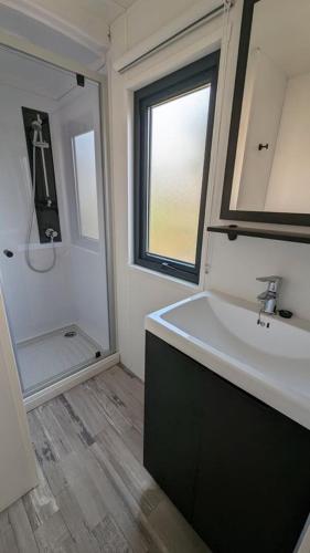 une salle de bain avec un lavabo blanc et un miroir dans l'établissement Mobil Home Premium 3 ch Camping 5 Biscarrosse Mayotte F62, à Biscarrosse
