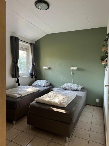two beds in a room with a green wall at Recreatiebungalow Lochem in Lochem