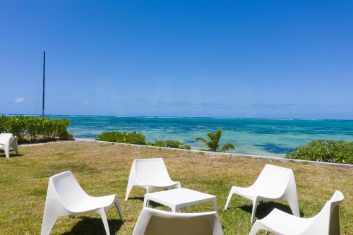 a group of white chairs sitting on the grass near the ocean at Beachfront & Pool Poste Lafayette in Poste Lafayette
