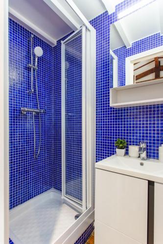 La salle de bains est pourvue de carrelage bleu, d'une douche et d'un lavabo. dans l'établissement Magnificent studio - 3P - Near Trocadéro, à Paris