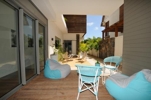 a patio with blue chairs and tables on a house at Beachfront & Pool Poste Lafayette in Poste Lafayette