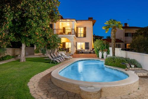 a backyard with a swimming pool and a house at Villa Magnolia Umag in Umag