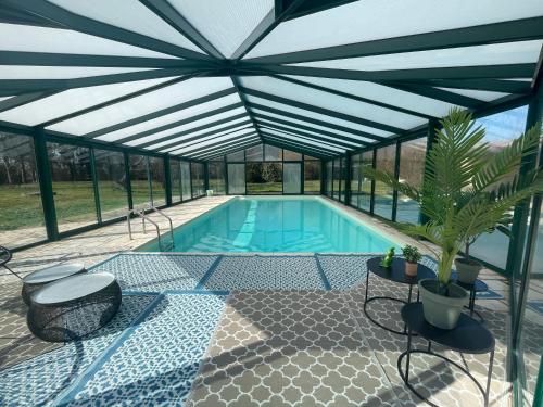 - une piscine dans une maison en verre avec un toit dans l'établissement Demeure de Charme de la Gravière, à Mably