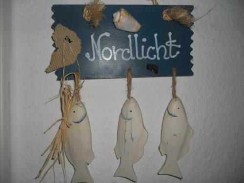 a sign with three narwhals hanging on a wall at Nordlicht im Haus Kaya, Hafenstraße in Wyk auf Föhr