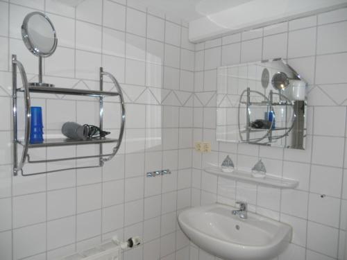 a white tiled bathroom with a sink and a mirror at Nordlicht im Haus Kaya, Hafenstraße in Wyk auf Föhr