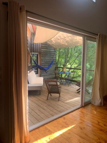 une porte coulissante en verre menant à un patio avec un hamac dans l'établissement maison en bois en bord d'Herault, à Saint-Bauzille-de-Putois