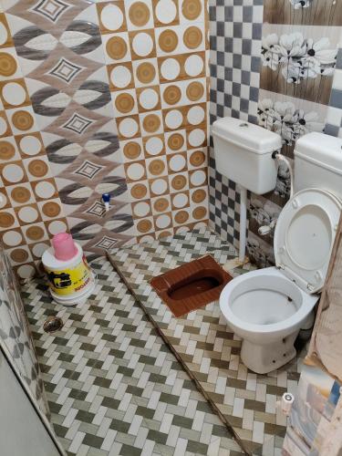 a bathroom with a toilet and a tiled floor at Hotel Janki Niwas - बाबा बैद्यनाथ मंदिर के निकट in Deoghar