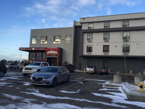 a parking lot with cars parked in front of a building at Southfort Inn in Fort Saskatchewan