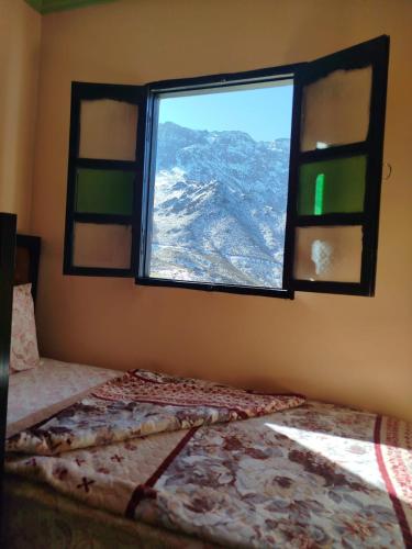 a bedroom with a bed and a window with a view at Gîte Assonfo Tachdirt in Tacheddirt