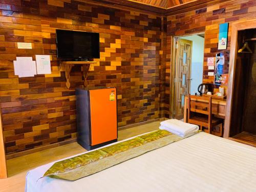 a room with a bed and a tv on a wall at Sangsawan Palace Khaolak Resort in Khao Lak