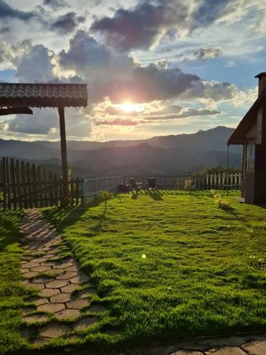 a view of a field with the sunset in the background at Chalé Mirante Da Guapiara in Aiuruoca