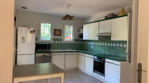 une cuisine avec des placards blancs et un comptoir vert dans l'établissement Villa climatisée dans Domaine privé Aix en Provence, à Aix-en-Provence