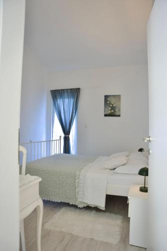 a white bedroom with a bed and a window at Apartman Nives in Kremena