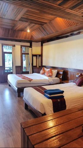 a bedroom with two beds in a room with wooden ceilings at Sangsawan Palace Khaolak Resort in Khao Lak