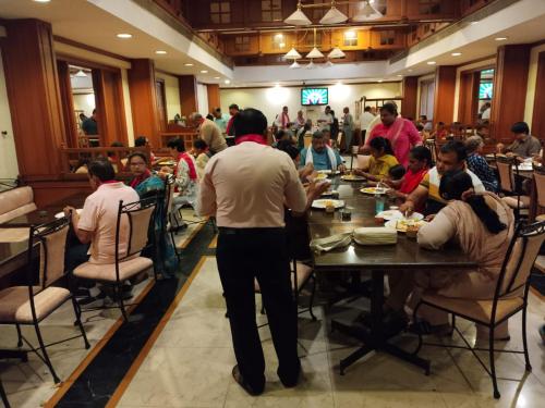 a group of people sitting at a table in a restaurant at Hotel Kalyan Residency in Tirupati