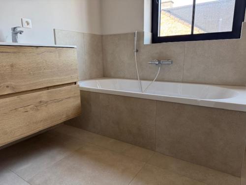 a bathroom with a bath tub and a window at Sœur in Berlare