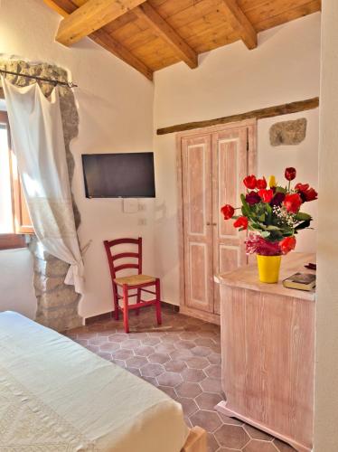 a bedroom with a bed and a vase of flowers at Regnos Altos boutique rooms in Bosa