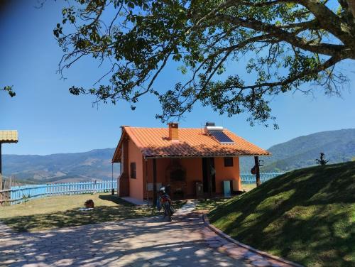 a small house with an orange roof on a hill at Chalé Mirante Da Guapiara in Aiuruoca
