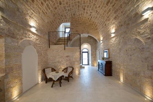 a room with a stone wall with a table and chairs at Baglio dei Mori in Donnalucata