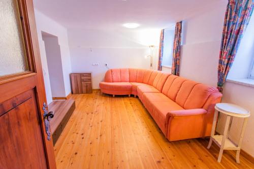 an orange couch in a living room with a wooden floor at Hoamathaus I by Alpenidyll Apartments in Gröbming