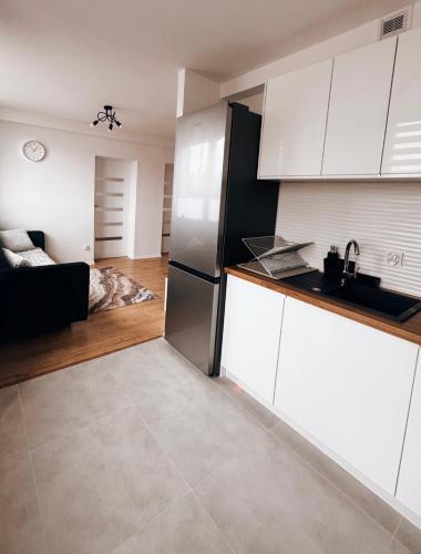 a kitchen with white cabinets and a black refrigerator at Apartament Świdnik Kosik in Świdnik