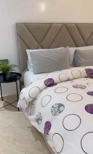 Una cama blanca con flores púrpuras. en Appartement de luxe à khouribga, en Khouribga