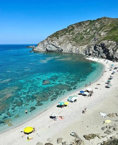 a beach with umbrellas and people in the water at Solmar Apartments in Biancareddu