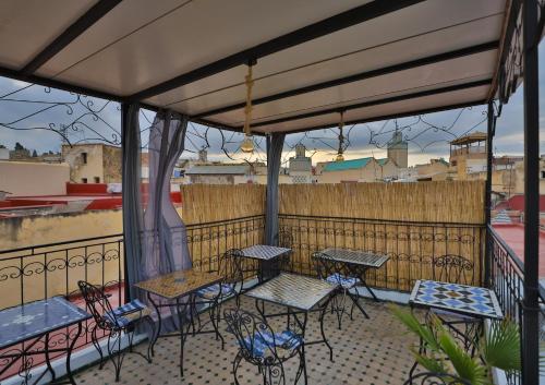 a patio with tables and chairs on a balcony at Dar Amazigh in Fès