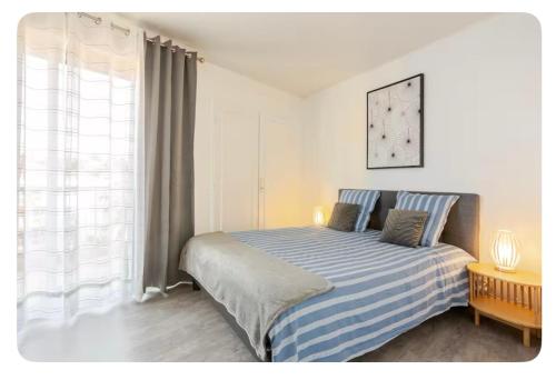 une chambre avec un lit à rayures bleues et blanches dans l'établissement TRIANGLE D OR 55m2 en bord de plage, à Saint-Raphaël