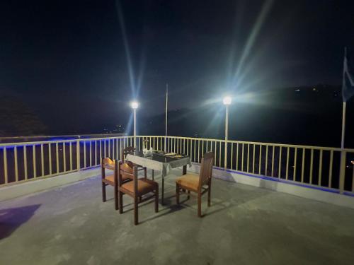 a table and chairs on a balcony at night at Hotel Mini Switzerland In Dalhousie #Air Cooled in Dalhousie