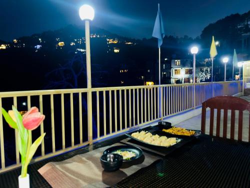 a table with plates of food on a balcony at night at Hotel Mini Switzerland In Dalhousie #Air Cooled in Dalhousie