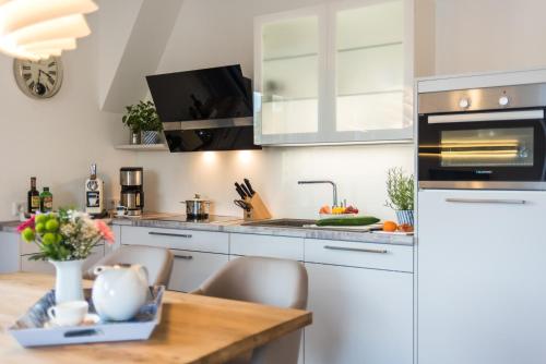 a kitchen with white cabinets and a wooden table at Victoria Luna Penthouse No 10 Strandstrstr48 in Zingst