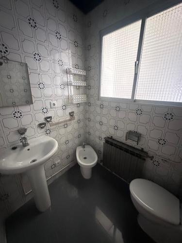 a bathroom with a sink and a toilet and a window at Casa Colón en la mancha in Herencia