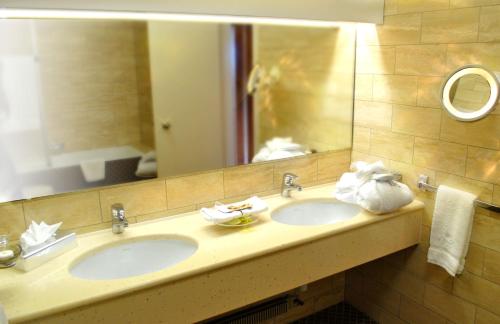 a bathroom with two sinks and a large mirror at Grand Hôtel du Golf & Palace in Crans-Montana
