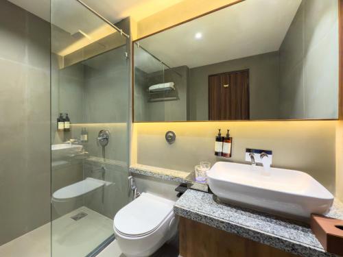 a bathroom with a sink and a toilet and a mirror at Regenta Dwarka in Dwarka