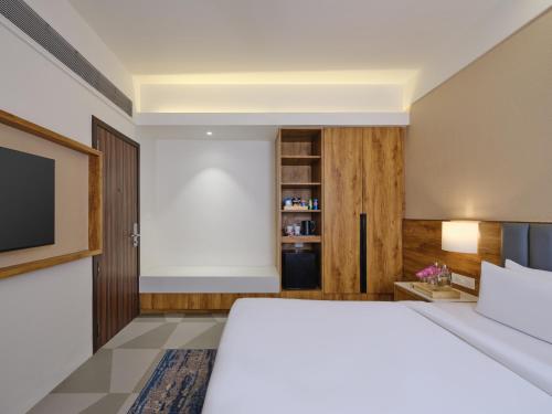 a bedroom with a bed and a flat screen tv at Regenta Dwarka in Dwarka