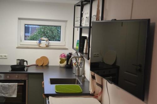 a kitchen with a black counter and a window at Nordapart Smutje in Butjadingen